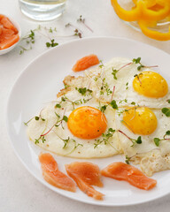 scrambled eggs with red fish on a white plate, daylight, light background, close-up, no people
