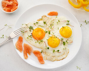 scrambled eggs with red fish on a white plate, daylight, light background, close-up, no people
