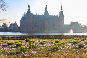 View of Frederiksborg castle in Hillerod, Denmark. Beautiful lake and garden with crocuses and...