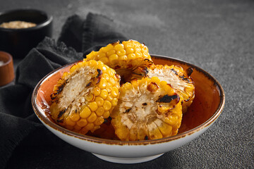 Charred and juicy grilled corn on the cob presented in a rustic orange bowl, an ideal summer...