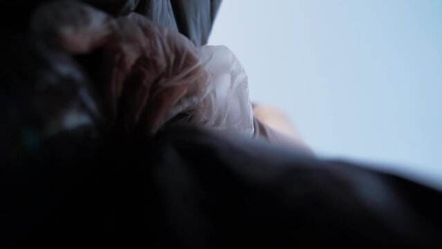 Garbage collection on the beach, a woman's hand puts garbage in a bag.