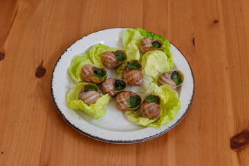 Escargots de Bourgogne (snails) seasoned with butter, parsley, garlic on wooden table