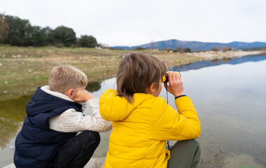 Children looking through binoculars at a lake