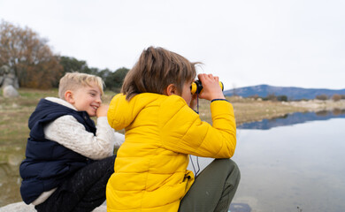 Children playing with binoculars in a lake in nature