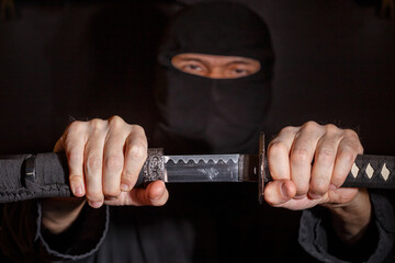 Ninja ready to fight, holding a Japanese sword. Photo of a warrior dressed in black clothes and...