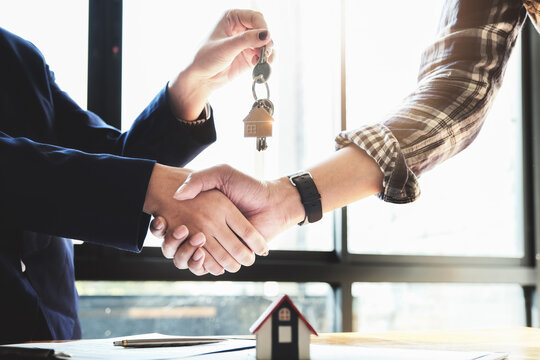 Focus on the congratulatory handshake. The real estate agent agrees to buy the home and hand the keys to the customer at the agent's office. conceptual agreement.