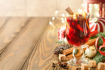 Christmas drinks hot mulled wine. Glass of mulled wine with aromatic spices cinnamon, anise, sugar and fir tree branches with bokeh and decorations. Traditional Xmas festive drink. Winter background.