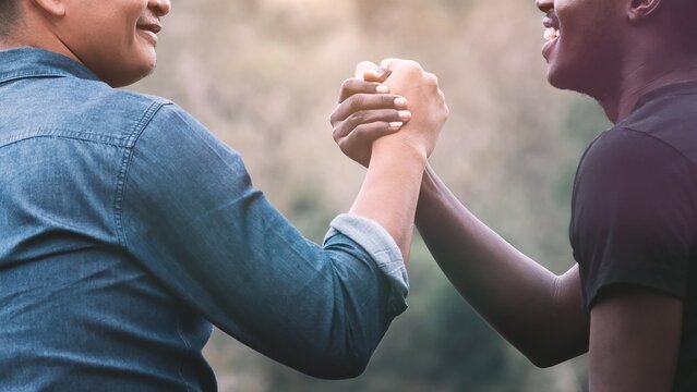 Holding hands of men of different skin colors Race and Ethnicity.Asian and African American friends holding hands, indistinguishable.