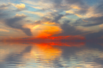 A horizontal image of a sunset over the ocean, where the iridescent rays of the sun penetrate the...