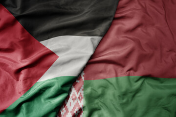big waving national colorful flag of belarus and national flag of palestine .