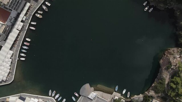Aerial top view 4k footage by drone of Voulismeni lake and Agios Nikolaos city on Crete, camera soar over dense build area and small round lake.