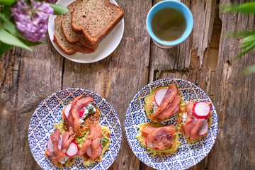 Draniki with cream cheese, trout, radish and dill on a blue plate. Top view, wooden background