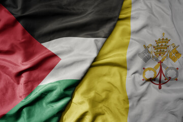 big waving national colorful flag of vatican city and national flag of palestine .