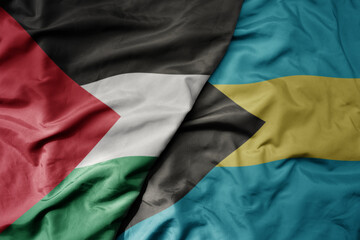 big waving national colorful flag of bahamas and national flag of palestine .