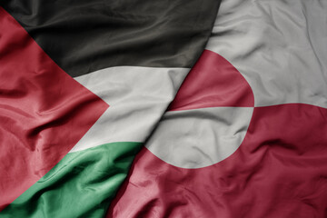 big waving national colorful flag of greenland and national flag of palestine .