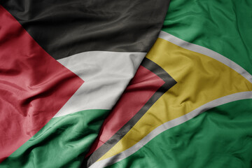 big waving national colorful flag of guyana and national flag of palestine .