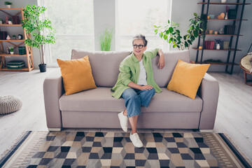 Full body size photo of thoughtful gray haired old lady sitting couch with two orange pillows...
