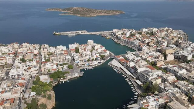 Aerial top view 4k footage by drone of Voulismeni lake and Agios Nikolaos city on Crete, camera soar over dense build area and small round lake.