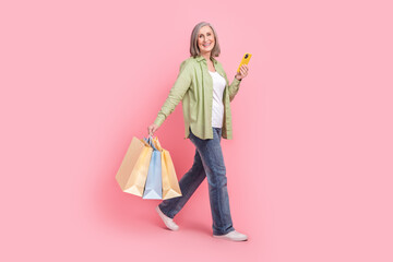 Full length photo of cheerful positive grandmother wear trendy clothes carry packs go store mall...