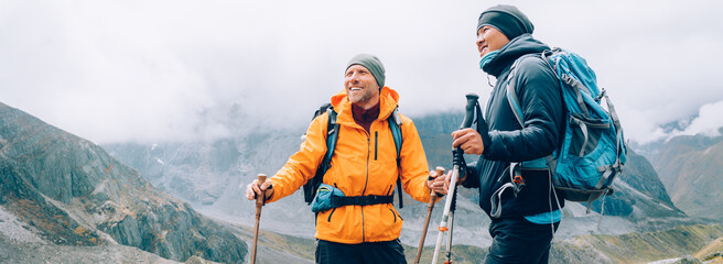 Caucasian and Sherpa men with backpacks with trekking poles together smiling enjoying Mera peak...