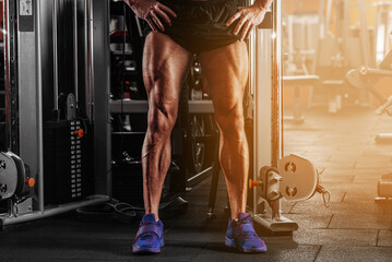 Closeup image of a strong man with muscular legs . posing at gym - obrazy, fototapety, plakaty