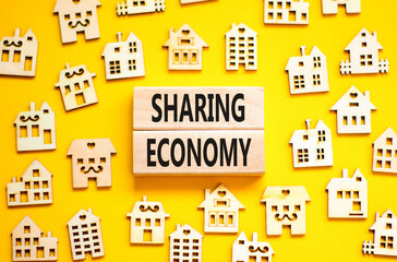 Sharing economy symbol. Concept words Sharing economy on beautiful wooden blocks. Beautiful yellow table yellow background. House model. Business sharing economy concept. Copy space.