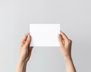 Female hands holding blank paper sheet on white background. Flat lay, top view.