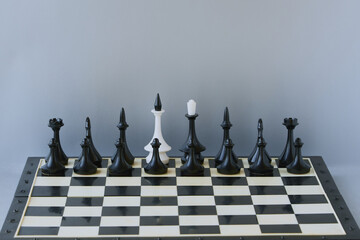 Black chess pieces stand on the board with the figure of a white king. Leader substitution, change...