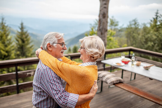 Romantic senior couple dancing on wooden cabin patio