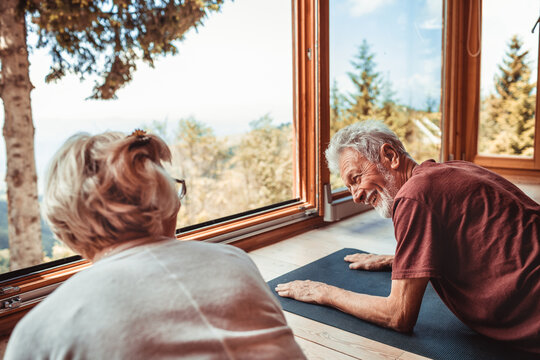 Fototapeta Senior couple doing yoga next to window with nature view at home
