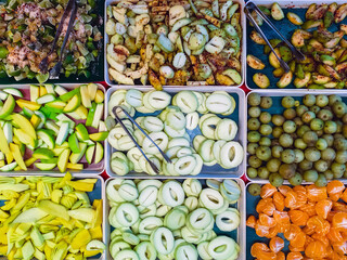 Top view of assorted fruits and pickled fruits on trays for sale in street market, healthy food concept Include high vitamin fruits, fresh fruits, Thai fruits, Street food.Variety fruits as background