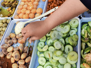 Hands of young woman choose to buy various kinds of fruits and pickled fruits, which popularly...