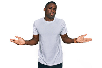 Young african american man wearing casual white t shirt clueless and confused with open arms, no idea concept.