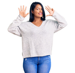 Hispanic woman with long hair wearing casual clothes showing and pointing up with fingers number...