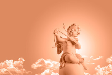 Color of the year 2024, Peachy Fuzz, Figurine of an angel Cupid on the podium with a bow and arrow on a blu sky with clouds background . Valentine's Day. - obrazy, fototapety, plakaty
