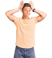 Young handsome man wearing casual clothes doing bunny ears gesture with hands palms looking cynical...