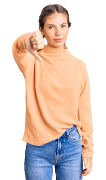 Beautiful caucasian woman with blonde hair wearing casual winter sweater looking unhappy and angry showing rejection and negative with thumbs down gesture. bad expression.
