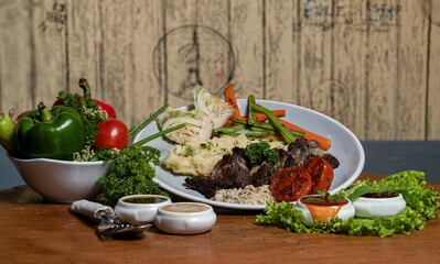 Grilled meat with vegetables and sauce on a wooden table in a restaurant