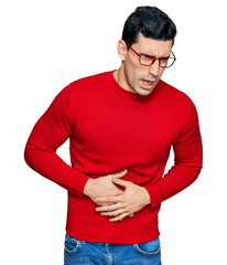 Handsome hispanic man wearing casual clothes and glasses with hand on stomach because nausea, painful disease feeling unwell. ache concept.