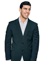 Handsome hispanic man wearing business clothes looking away to side with smile on face, natural expression. laughing confident.