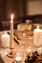 Obraz na płótnie Canvas holidays, dinner party and celebration concept - close up of festive table serving with champagne in glass and burning candles