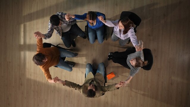 In The Shot Above A Group Of People, A Man And A Woman And Their Mentor Are Sitting On A Chair. They Have Come To A Meeting, A Session, Therapy. They Are Sitting In A Circle Holding Hands. Top View