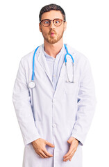 Fototapeta premium Handsome young man with bear wearing doctor uniform making fish face with lips, crazy and comical gesture. funny expression.