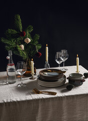winter holidays, dinner party and celebration concept - crockery and candles for scandinavian christmas table serving over black background