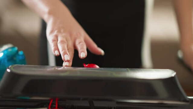 Lady commences treadmill by activating start button closeup. Woman sets speed of gym apparatus for indoor fitness sessions. Technology in sports equipment