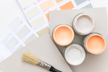 Tiny sample paint cans during house renovation, process of choosing paint for the walls, Peach Fuzz color of the year 2024, color charts on background - obrazy, fototapety, plakaty