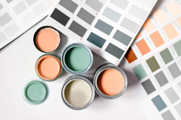 Tiny sample paint cans during house renovation, process of choosing paint for the walls, Peach Fuzz color of the year 2024, color charts on background