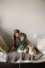 Young woman with corgi dog on the bed in bedroom