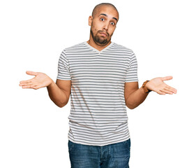 Hispanic adult man wearing casual clothes clueless and confused expression with arms and hands...