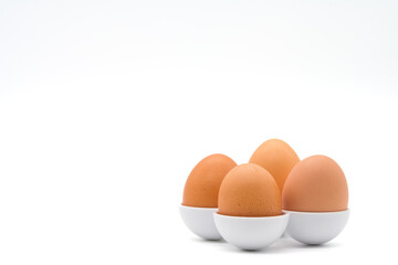 Four chicken eggs in different sizes in egg holders isolated on a white background